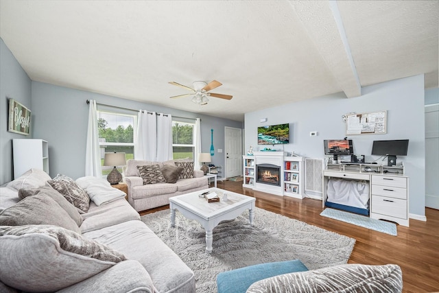 258 Green Meadow Dr, Smithville, TN 37166 - living area with wood finished floors, ceiling fan, a warm lit fireplace, beam ceiling, and a textured ceiling