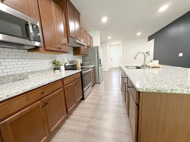 101 Percheron Pl, Smyrna, TN 37167 - kitchen featuring stainless steel appliances, under cabinet range hood, light wood-style flooring, backsplash, and an island with sink