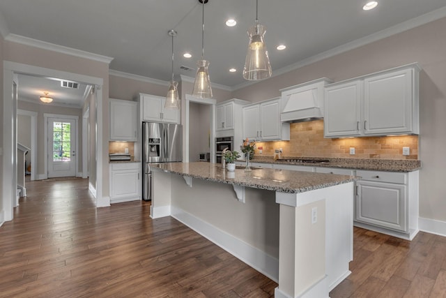 1074 Amelia Park Dr, Franklin, TN 37067 - kitchen featuring stainless steel appliances, custom exhaust hood, white cabinets, an island with sink, and ornamental molding