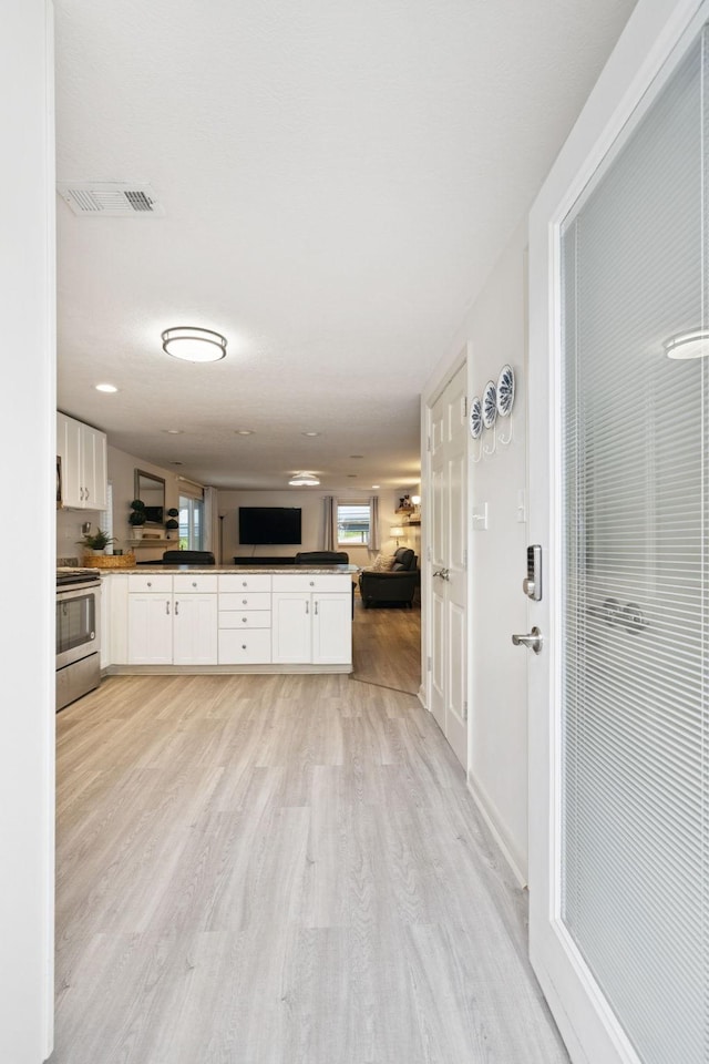 617 Still Point Rd, Smithville, TN 37166 - kitchen with stainless steel electric range, open floor plan, dark countertops, light wood-style flooring, and white cabinetry