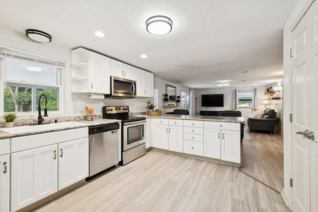 617 Still Point Rd, Smithville, TN 37166 - kitchen featuring appliances with stainless steel finishes, a peninsula, open floor plan, white cabinets, and light wood-style floors