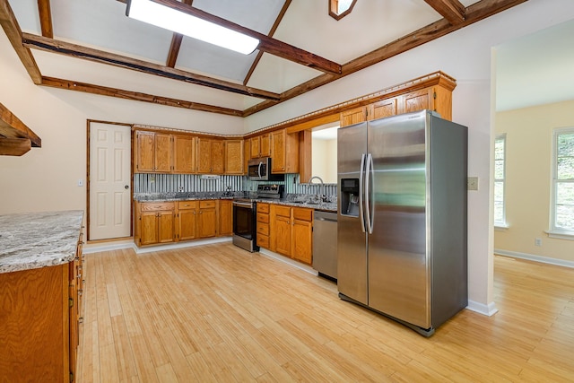5141 Tranham Rd, Whites Creek, TN 37189 - kitchen featuring appliances with stainless steel finishes, brown cabinetry, tasteful backsplash, light wood-type flooring, and beamed ceiling