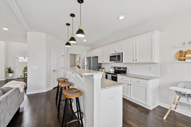 9007 Outpost Dr, Spring Hill, TN 37174 - kitchen with appliances with stainless steel finishes, dark wood finished floors, a breakfast bar area, white cabinetry, and recessed lighting