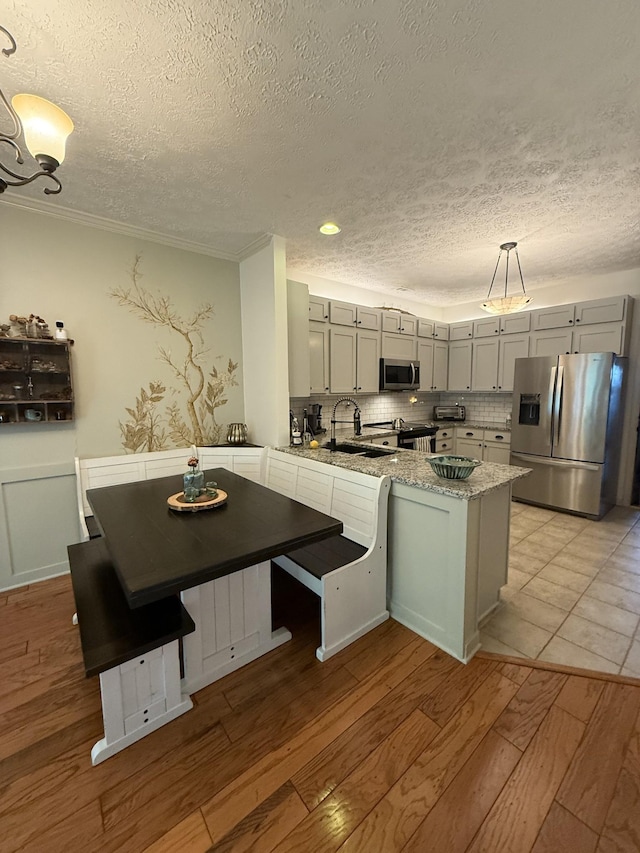 3141 Tristan Dr, Franklin, TN 37064 - kitchen with appliances with stainless steel finishes, a textured ceiling, a peninsula, light wood finished floors, and gray cabinets