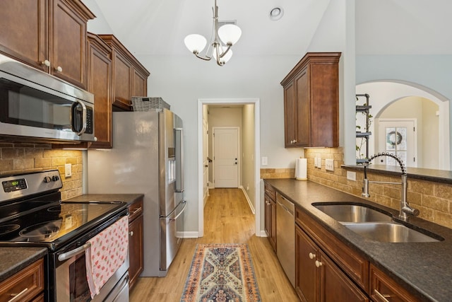 3022 Honeysuckle Dr, Spring Hill, TN 37174 - kitchen featuring stainless steel appliances, arched walkways, light wood finished floors, and backsplash