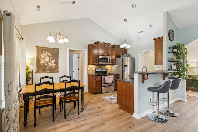 3022 Honeysuckle Dr, Spring Hill, TN 37174 - kitchen featuring appliances with stainless steel finishes, a chandelier, dark countertops, light wood finished floors, and a breakfast bar