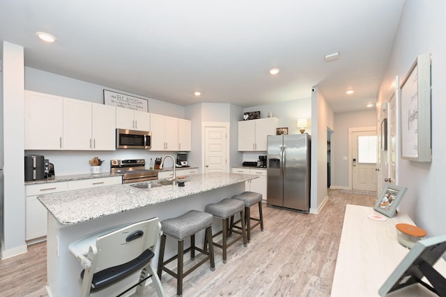 2004 Hardwick Ln, Gallatin, TN 37066 - kitchen with appliances with stainless steel finishes, a breakfast bar area, white cabinets, light wood-style flooring, and recessed lighting