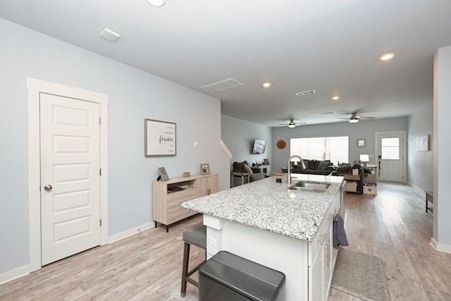 2004 Hardwick Ln, Gallatin, TN 37066 - kitchen featuring a kitchen island with sink, light wood-type flooring, open floor plan, light stone countertops, and recessed lighting