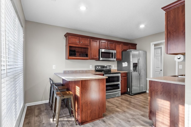 2276 Yeager Dr, Clarksville, TN 37040 - kitchen with appliances with stainless steel finishes, a peninsula, light wood-style floors, a breakfast bar, and light countertops