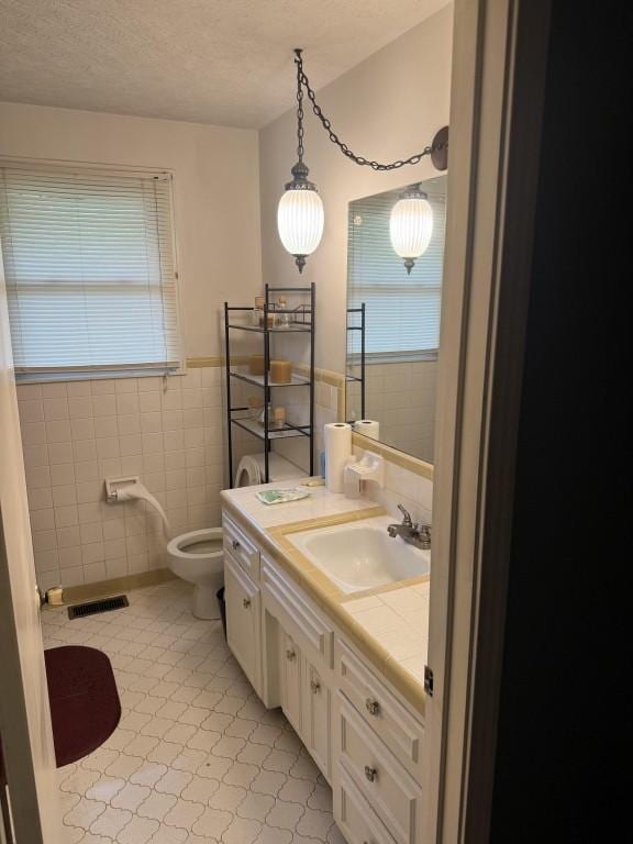 2503 Hickory Dr, Springfield, TN 37172 - bathroom featuring tile walls, healthy amount of natural light, vanity, a textured ceiling, and a wainscoted wall