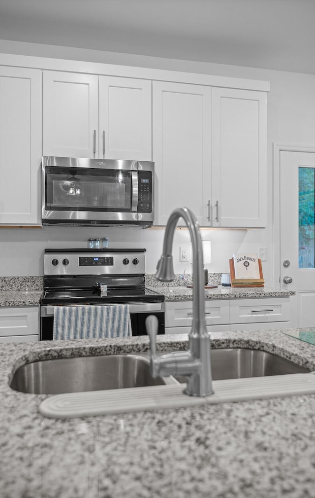 9407 Hackberry Ln, Soddy Daisy, TN 37379 - kitchen with stainless steel appliances, white cabinets, and light stone counters