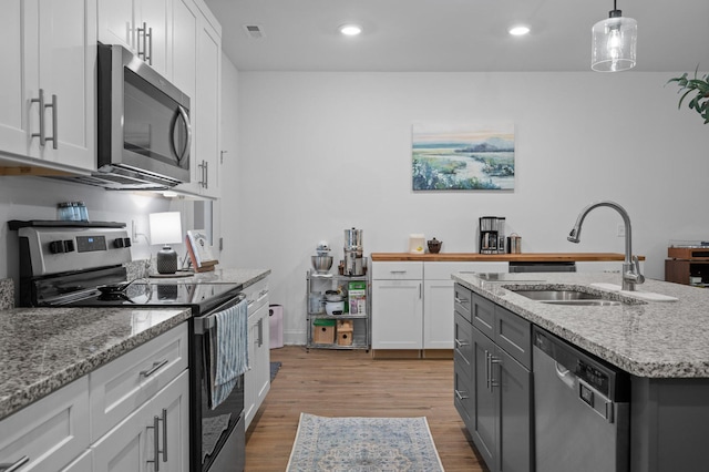 9407 Hackberry Ln, Soddy Daisy, TN 37379 - kitchen featuring stainless steel appliances, white cabinetry, wood finished floors, light stone counters, and hanging light fixtures