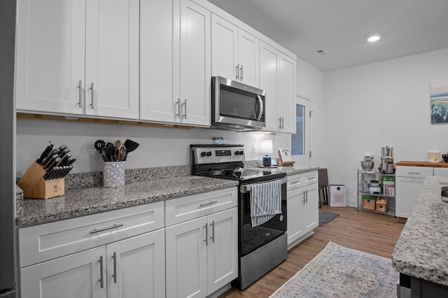 9407 Hackberry Ln, Soddy Daisy, TN 37379 - kitchen with appliances with stainless steel finishes, white cabinets, light wood-style flooring, light stone countertops, and recessed lighting