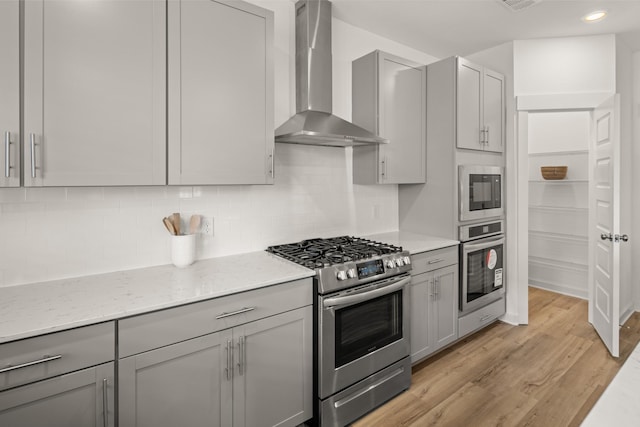582 Gingerwood Ln, Hendersonville, TN 37075 - kitchen with stainless steel appliances, wall chimney exhaust hood, gray cabinets, light wood-style flooring, and backsplash
