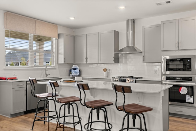 582 Gingerwood Ln, Hendersonville, TN 37075 - kitchen featuring appliances with stainless steel finishes, wall chimney exhaust hood, gray cabinetry, light countertops, and light wood-style floors