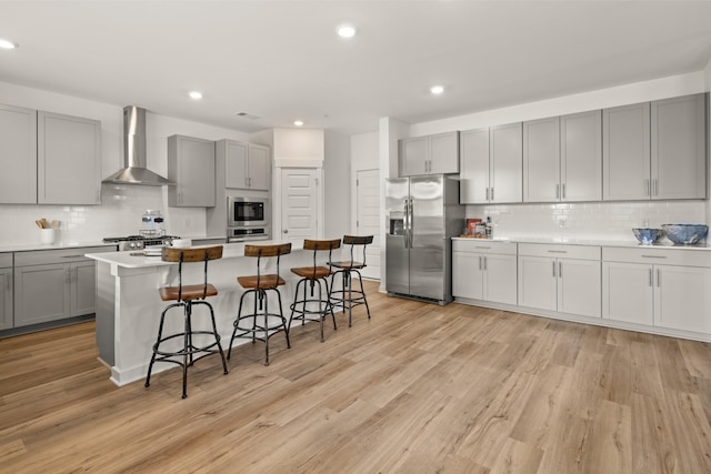 582 Gingerwood Ln, Hendersonville, TN 37075 - kitchen with wall chimney range hood, appliances with stainless steel finishes, gray cabinetry, tasteful backsplash, and a kitchen bar