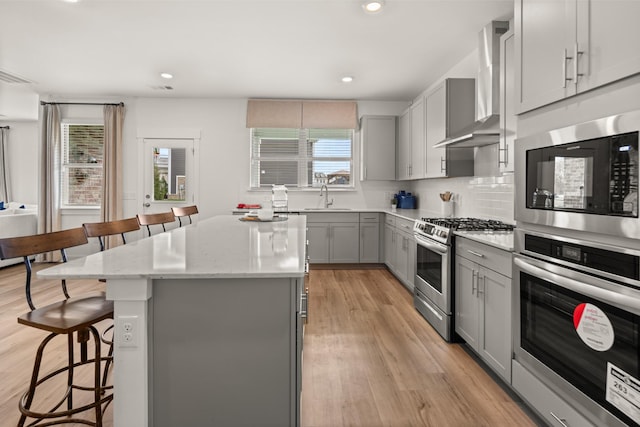 582 Gingerwood Ln, Hendersonville, TN 37075 - kitchen with appliances with stainless steel finishes, gray cabinets, a kitchen bar, a center island, and light wood-type flooring