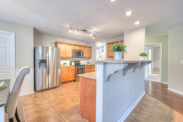 5451 Middlebury Dr, Murfreesboro, TN 37128 - kitchen with appliances with stainless steel finishes, light tile patterned floors, a kitchen bar, recessed lighting, and light countertops