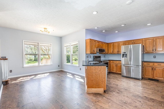 1622 Hickory Valley Rd, Lebanon, TN 37087 - kitchen with stainless steel appliances, a textured ceiling, dark countertops, brown cabinetry, and wood finished floors