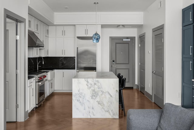 1616 W End Ave Unit 2609, Nashville, TN 37203 - kitchen with under cabinet range hood, appliances with stainless steel finishes, decorative backsplash, white cabinetry, and a kitchen island