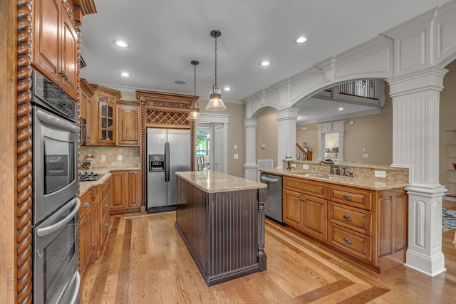 2711 Crowne Pointe Dr, Murfreesboro, TN 37130 - kitchen featuring decorative columns, stainless steel appliances, a center island, brown cabinetry, and light wood-style floors