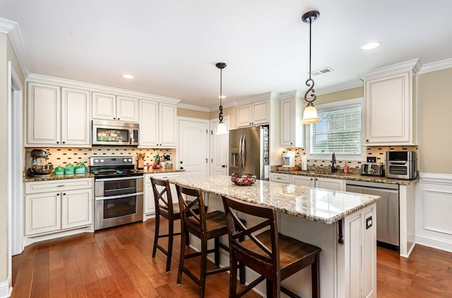 212 Hickory Pointe Dr, Lebanon, TN 37087 - kitchen featuring stainless steel appliances, dark wood finished floors, crown molding, a kitchen breakfast bar, and a kitchen island
