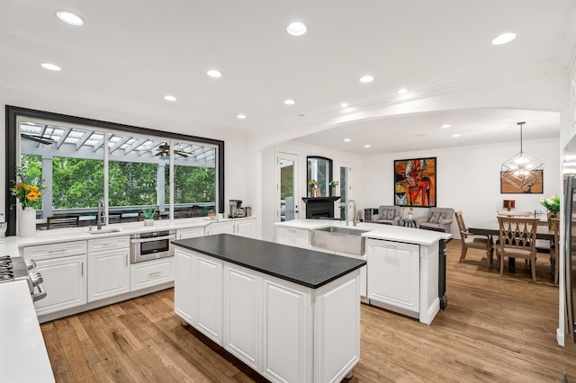 7871 Oscar Green Rd, Primm Springs, TN 38476 - kitchen featuring a center island, arched walkways, ornamental molding, white cabinets, and light wood-type flooring