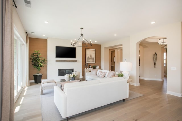 1935 Harmony Rd, Spring Hill, TN 37174 - living area with light wood-type flooring, a large fireplace, arched walkways, a chandelier, and recessed lighting