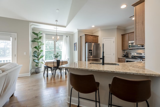 8624 Reba Ln, Hixson, TN 37343 - kitchen featuring appliances with stainless steel finishes, light stone countertops, a kitchen breakfast bar, ornamental molding, and a chandelier