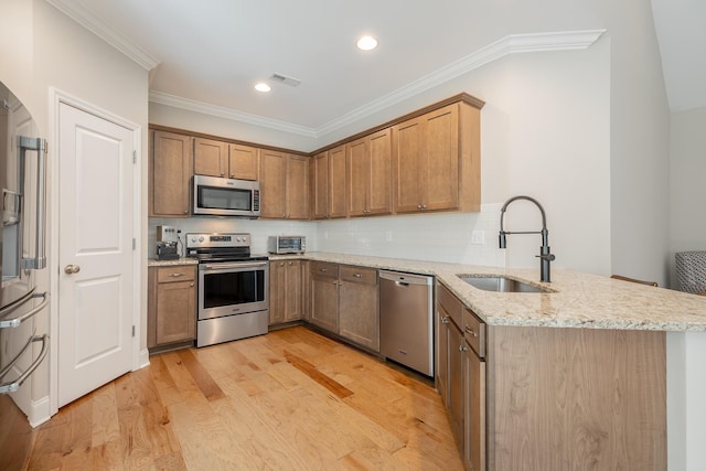 8624 Reba Ln, Hixson, TN 37343 - kitchen featuring stainless steel appliances, a peninsula, ornamental molding, light stone counters, and light wood-style floors