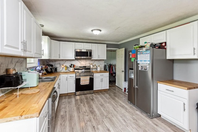 330 Union Camp Rd, Lafayette, TN 37083 - kitchen featuring wooden counters, appliances with stainless steel finishes, white cabinetry, light wood finished floors, and decorative backsplash