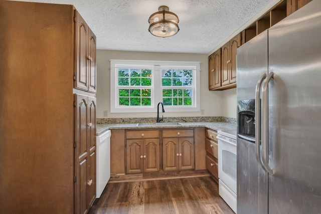3328 Church St, Burns, TN 37029 - kitchen featuring white appliances, dark wood-style flooring, brown cabinetry, a textured ceiling, and light stone counters