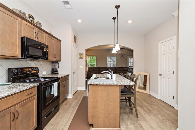 433 Longstone Rd, Gallatin, TN 37066 - kitchen with black appliances, arched walkways, a breakfast bar area, light wood-type flooring, and decorative backsplash