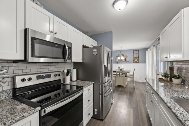 516 Cedarcrest Dr, Chapmansboro, TN 37035 - kitchen with stainless steel appliances, dark wood-style floors, white cabinetry, and wainscoting