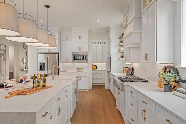3005 Littlebury Park Dr, Thompsons Station, TN 37179 - kitchen with stainless steel appliances, white cabinetry, light wood-type flooring, decorative backsplash, and a center island with sink