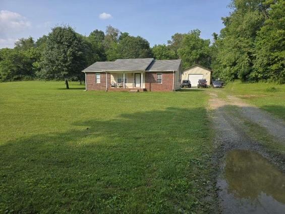1726 Old Clarksville Pike, Chapmansboro, TN 37035 - single story home with a front yard, a porch, a garage, and dirt driveway