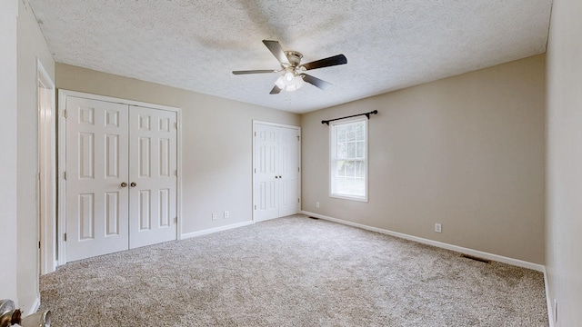 1726 Old Clarksville Pike, Chapmansboro, TN 37035 - unfurnished bedroom featuring two closets, carpet, a textured ceiling, and a ceiling fan