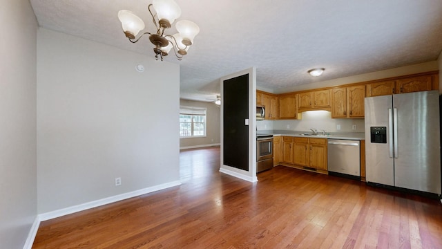 1726 Old Clarksville Pike, Chapmansboro, TN 37035 - kitchen with appliances with stainless steel finishes, light countertops, a chandelier, wood finished floors, and pendant lighting
