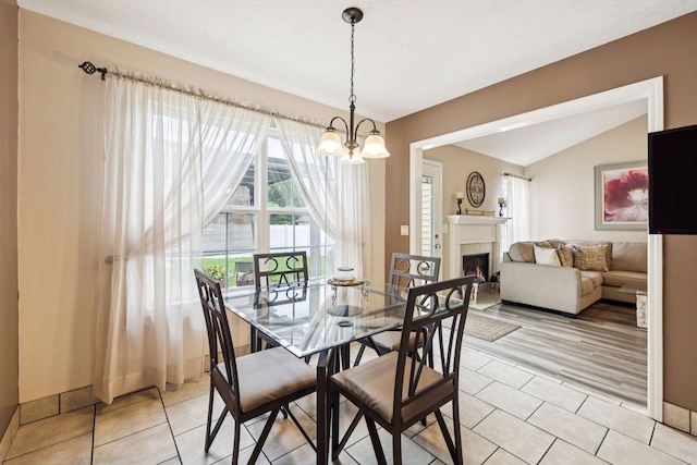 1652 Saint Andrews Dr, Murfreesboro, TN 37128 - dining area with a chandelier, a warm lit fireplace, light tile patterned floors, and lofted ceiling