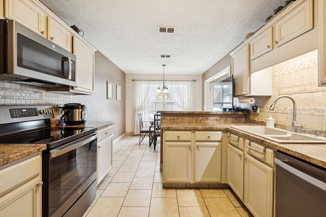 1652 Saint Andrews Dr, Murfreesboro, TN 37128 - kitchen featuring appliances with stainless steel finishes, cream cabinetry, a peninsula, a textured ceiling, and tasteful backsplash