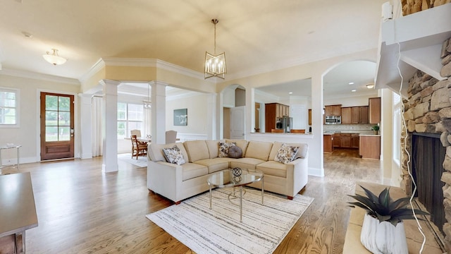 166 Azalea Ln, Franklin, TN 37064 - living room with ornamental molding, light wood-style flooring, arched walkways, decorative columns, and a fireplace