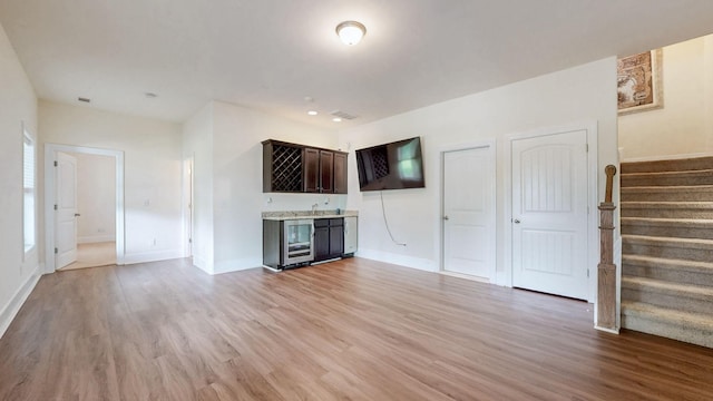 166 Azalea Ln, Franklin, TN 37064 - unfurnished living room featuring bar with sink, light wood-style flooring, stairway, and wine cooler