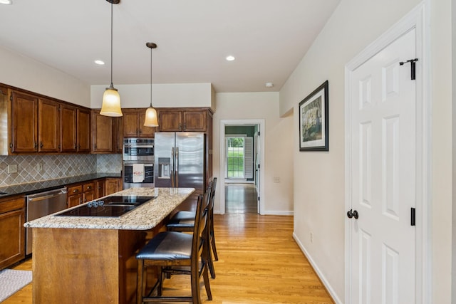 410 Ridge View Ct, Franklin, TN 37067 - kitchen with appliances with stainless steel finishes, light wood-type flooring, tasteful backsplash, a breakfast bar area, and a center island
