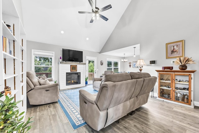 541 Macy Lynn Dr, Clarksville, TN 37042 - living room with a glass covered fireplace, a ceiling fan, wood finished floors, high vaulted ceiling, and a chandelier
