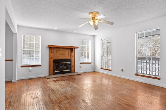 14319 Bluffview Dr, Birchwood, TN 37308 - unfurnished living room with a ceiling fan, a textured ceiling, healthy amount of natural light, a glass covered fireplace, and wood-type flooring