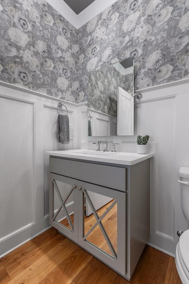 2305 Weeping Willow Dr, Ooltewah, TN 37363 - half bath with wallpapered walls, a decorative wall, vanity, wainscoting, and wood finished floors