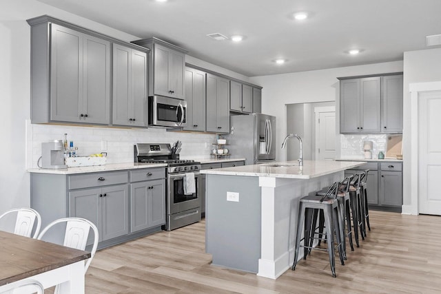 2129 Firelight Way, Ooltewah, TN 37363 - kitchen featuring stainless steel appliances, gray cabinets, tasteful backsplash, a breakfast bar, and recessed lighting
