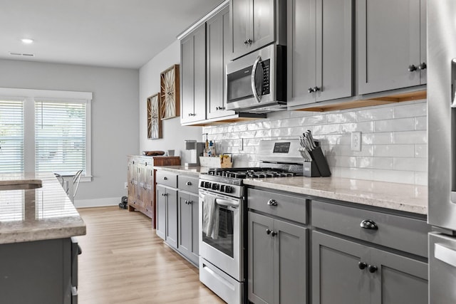 2129 Firelight Way, Ooltewah, TN 37363 - kitchen with appliances with stainless steel finishes, gray cabinets, tasteful backsplash, and light stone counters