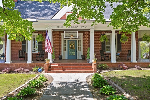 302 S Main St, La Fayette, GA 30728 - view of exterior entry featuring a porch, brick siding, roof with shingles, and a lawn