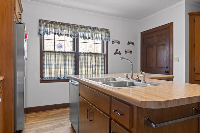 3216 Cleveland Hwy, Dalton, GA 30721 - kitchen featuring appliances with stainless steel finishes, light wood-style flooring, crown molding, wood counters, and a kitchen island with sink